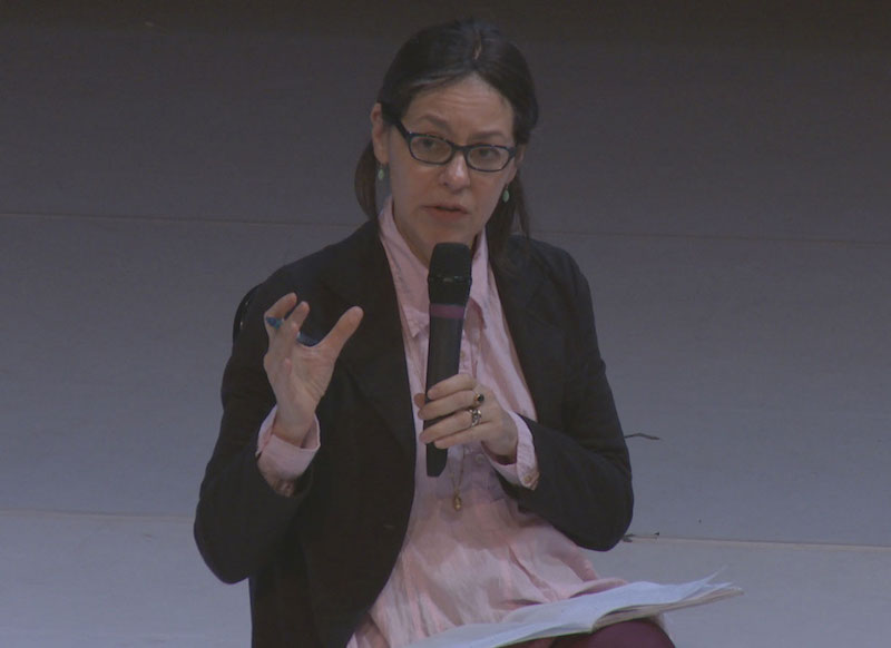 A close up of Panelist Annie B. Parson in a pink button up, dark blazer and glasses